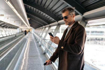 Man standing near railing using smart phone