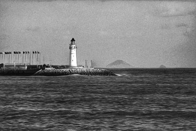 Lighthouse by sea against sky