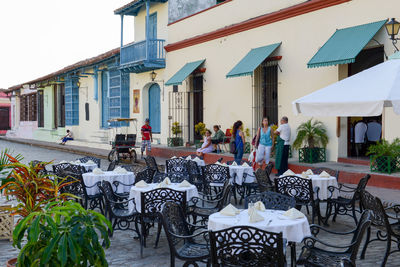 Chairs and tables at sidewalk cafe against clear sky