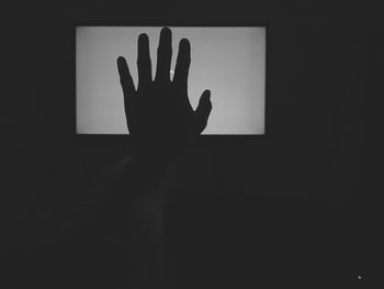 Silhouette of man touching illuminated light