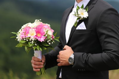 Midsection of man holding flower bouquet