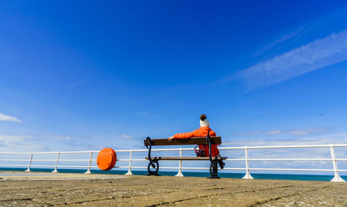 Woman sitting on beach against sky