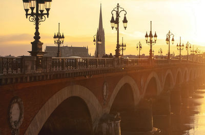 Arch bridge over river against sky in city