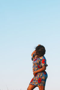 Side view of woman standing against clear sky