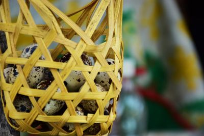 Close-up of quail eggs in wicker basket hanging at home