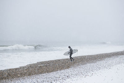 Man on snow covered land against sea