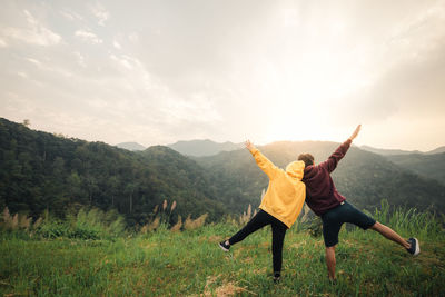 Rear view of couple with arms outstretched standing on mountain