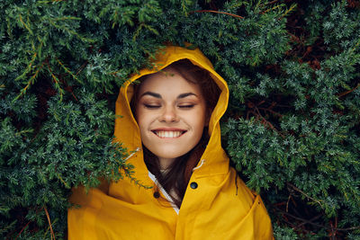 Portrait of young woman standing against plants