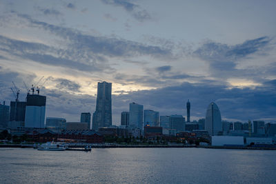 Sea by modern buildings against sky in city