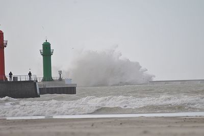 Lighthouse by sea against clear sky