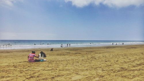 People sitting on beach against sky