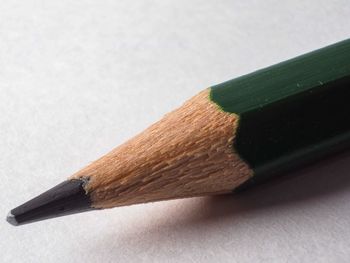 Close-up of green wood pencil on table against white background