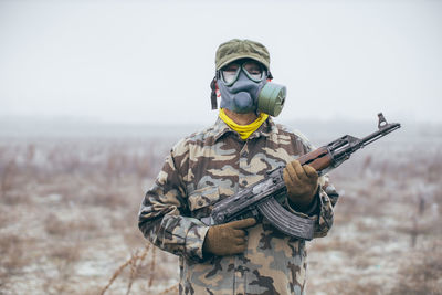 Portrait of soldier holding rifle standing against snow covered land during winter