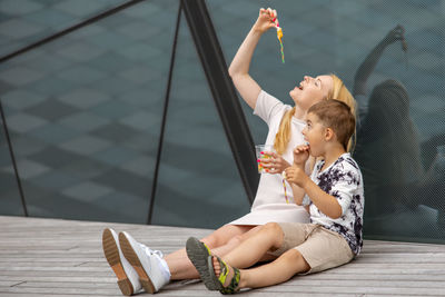 Happy blond woman and little boy sitting on terrace and eating sweets. mother and son