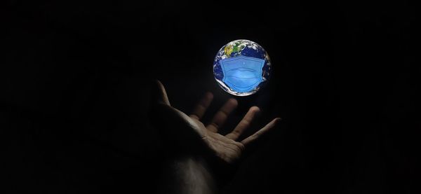 Person holding glass against black background