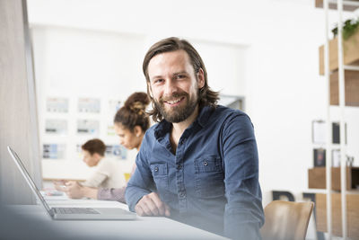 Smiling man in office with laptop