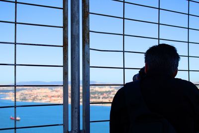 Rear view of man looking through window