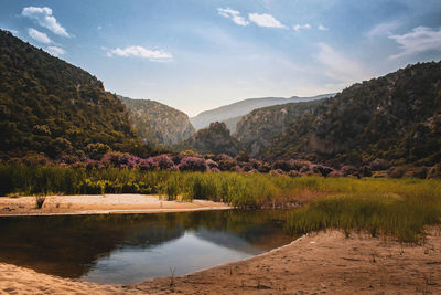 Scenic view of lake by mountains against sky