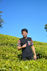 Portrait of smiling young man standing on tea plantation