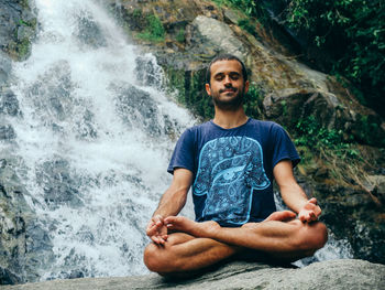 Portrait of man meditating by waterfall