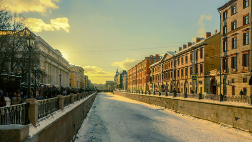 Street amidst buildings against sky during sunset
