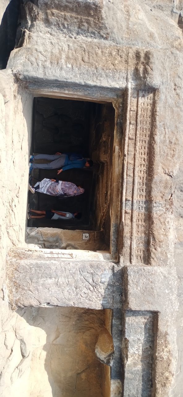 architecture, ancient history, built structure, adult, history, temple, men, ruins, day, sunlight, travel, the past, building exterior, cob, women, full length, nature, ancient, wall, leisure activity, tourism, lifestyles, outdoors, travel destinations, two people, entrance, building, doorway, door, old ruin, rock, religion