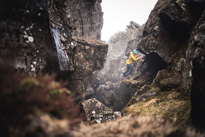 Woman in yellow jacket exploring thermal fissures in iceland