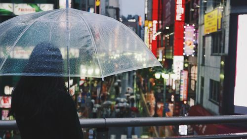 Rear view of woman with umbrella in city