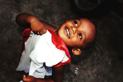 High angle view of smiling baby boy looking up while standing outdoors