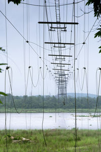 Low angle view of abandoned cable bridge against sky