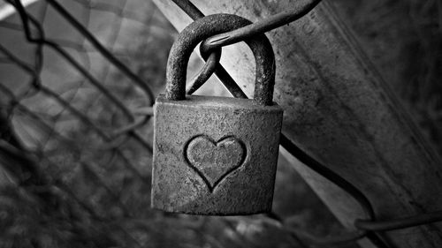 Close-up of love padlock hanging on fence