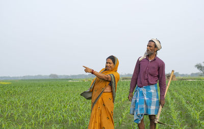Woman standing on agricultural field against clear sky
