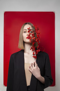 Blond woman holding twig in front of blank red frame against white background