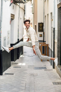 Portrait of cheerful man jumping at alley