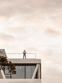 Low angle view of man standing at terrace against sky