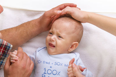 Man and woman holding son crying on bed at home