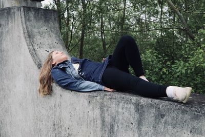 Low section of woman sitting on tree trunk