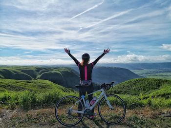 Rear view of person with bicycle standing on landscape