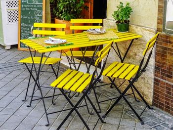 Empty chairs and tables at sidewalk cafe against building