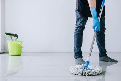 Low section of man cleaning tiled floor