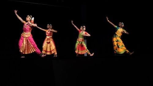 Group of people dancing against black background