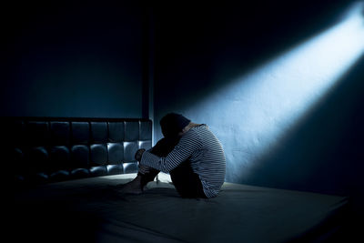 Side view of man sitting on wall