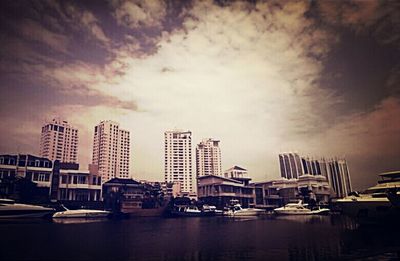 Boats in harbor against cloudy sky