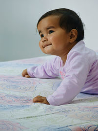 Close-up portrait of baby girl on bed