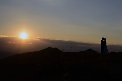 Silhouette man standing on mountain during sunset