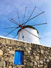 Low angle view of traditional windmill by wall against sky