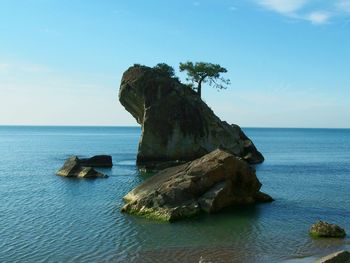 Rock formation by sea against sky