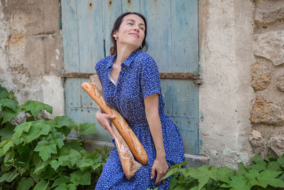 Young woman standing with french baguettes in the countryside