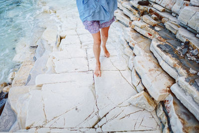 Low section of woman walking on stone steps at beach