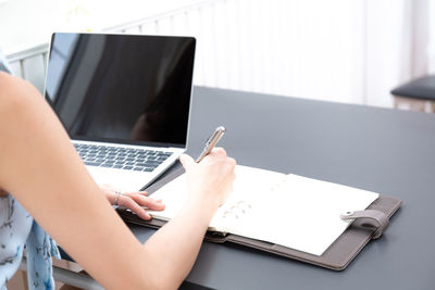 Low angle view of person using laptop on table